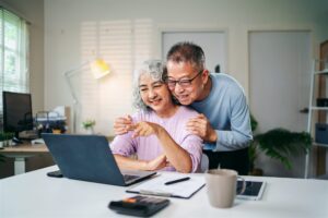 Senior Couple Enjoying Retirement Planning Online Together at Home Using Laptop Computer Searching for Investment Ideas and Financial Security