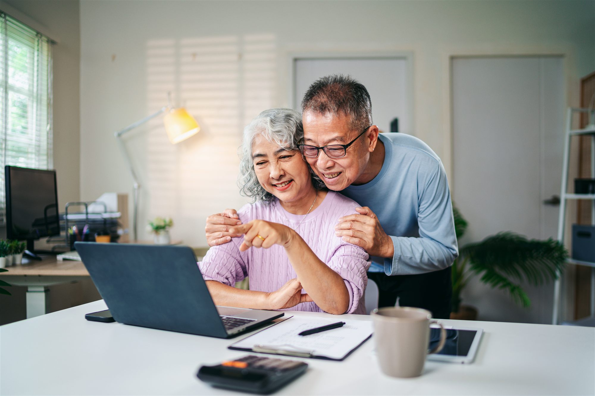 Senior Couple Enjoying Retirement Planning Online Together at Home Using Laptop Computer Searching for Investment Ideas and Financial Security